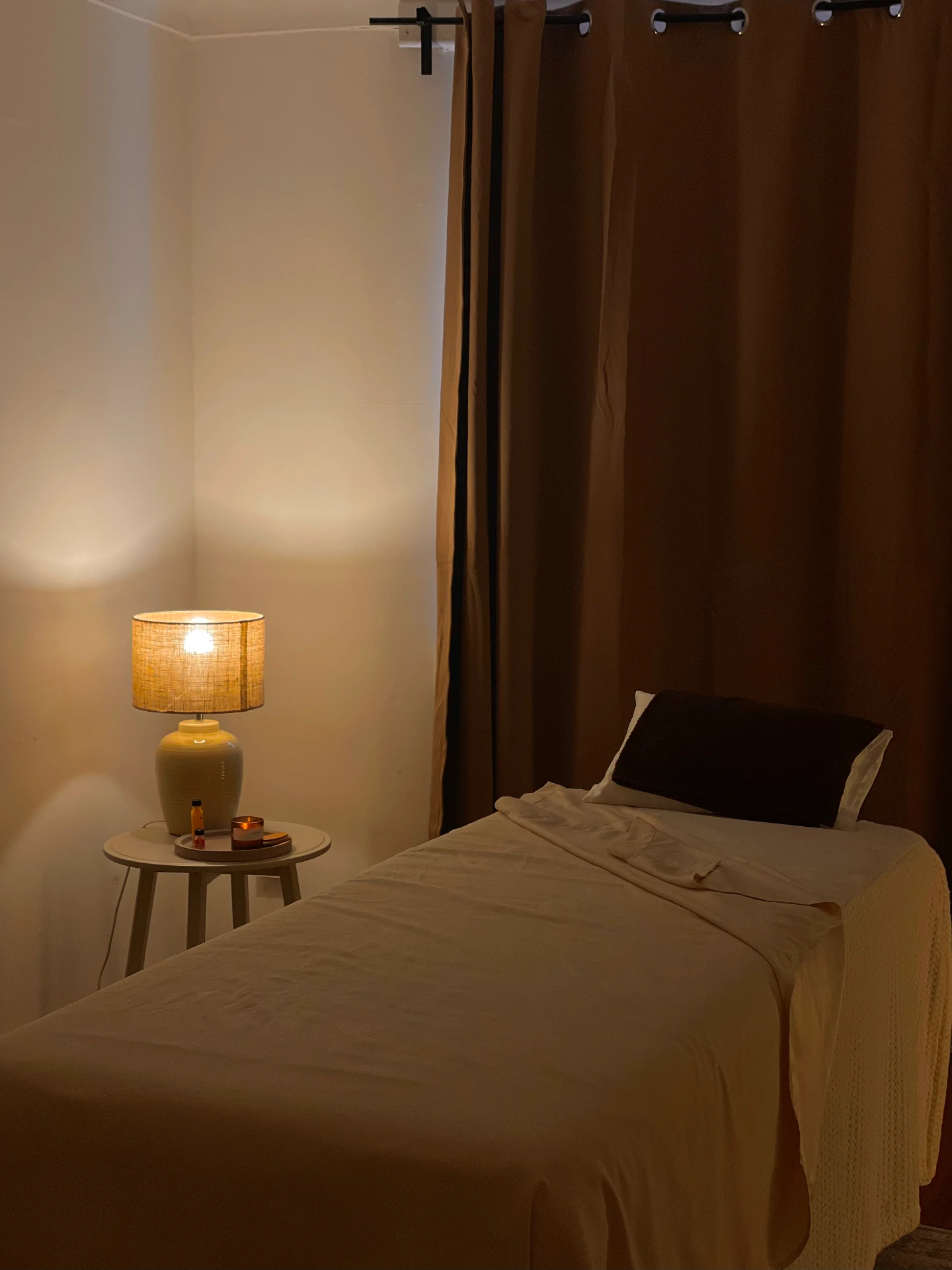 The FLOW treatment room by lamplight — dressed table, linen and amber oils